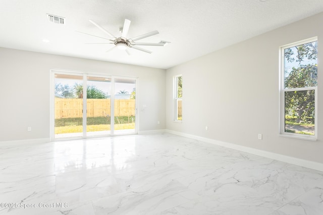 empty room with ceiling fan and a textured ceiling