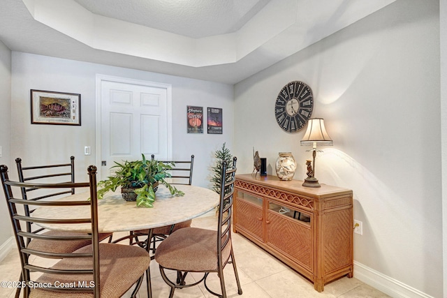 dining room featuring light tile patterned flooring, a tray ceiling, and a textured ceiling