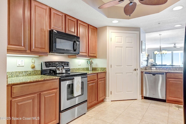 kitchen with light stone counters, light tile patterned floors, pendant lighting, stainless steel appliances, and ceiling fan with notable chandelier