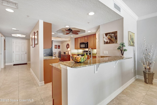 kitchen with a breakfast bar area, light stone countertops, kitchen peninsula, and a textured ceiling