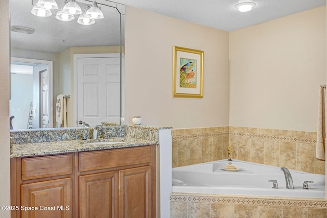 bathroom featuring vanity, tiled bath, and a textured ceiling