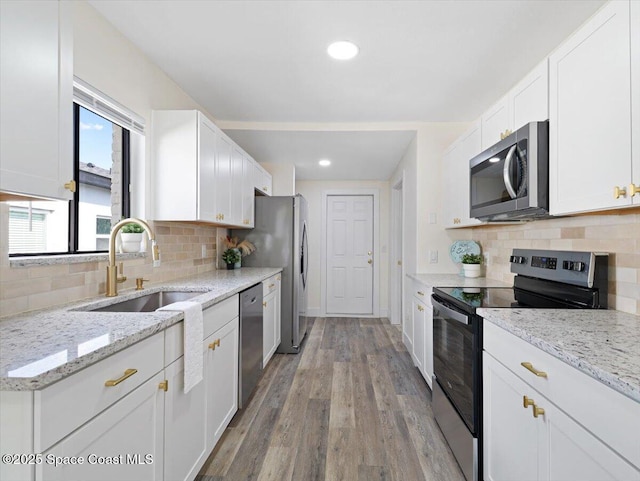 kitchen featuring light hardwood / wood-style flooring, sink, light stone counters, stainless steel appliances, and white cabinets