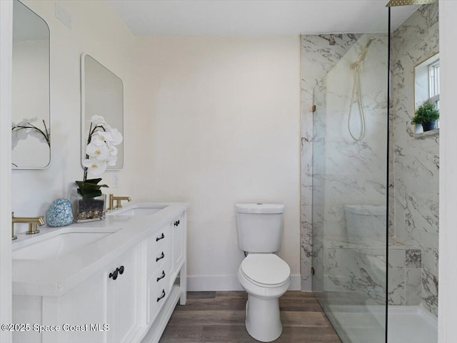 bathroom with toilet, vanity, hardwood / wood-style floors, and tiled shower