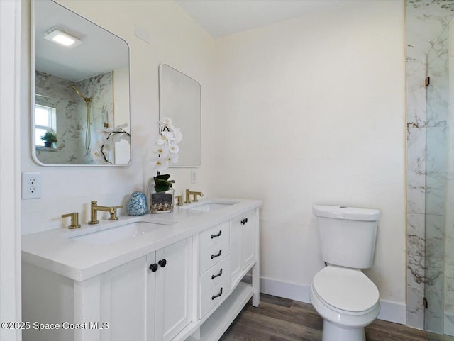 bathroom with hardwood / wood-style flooring, vanity, a tile shower, and toilet