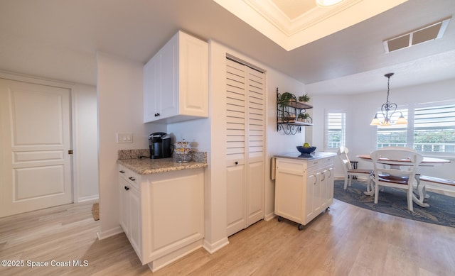 kitchen featuring white cabinetry, ornamental molding, pendant lighting, and light hardwood / wood-style floors