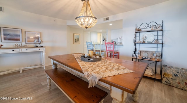 dining space with a notable chandelier and light hardwood / wood-style flooring