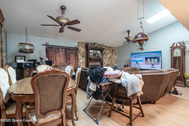 dining area with lofted ceiling, a textured ceiling, ceiling fan, and light hardwood / wood-style flooring