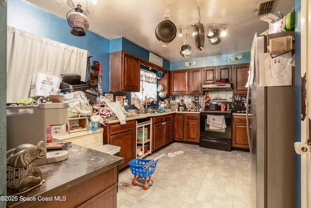 kitchen featuring black range with electric stovetop, sink, backsplash, and stainless steel refrigerator