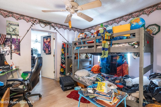 bedroom featuring ceiling fan, light hardwood / wood-style flooring, and a textured ceiling