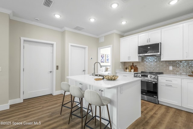 kitchen with white cabinetry, stainless steel appliances, and a center island with sink