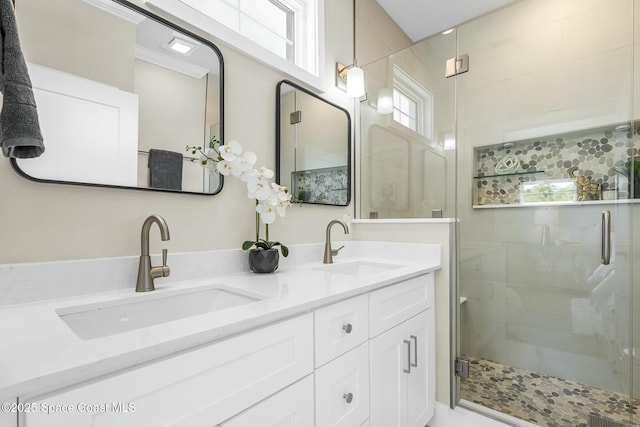 bathroom featuring a shower with door and vanity