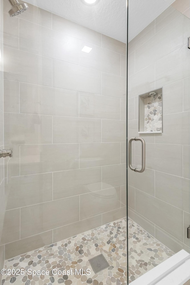 bathroom featuring a shower with shower door and a textured ceiling