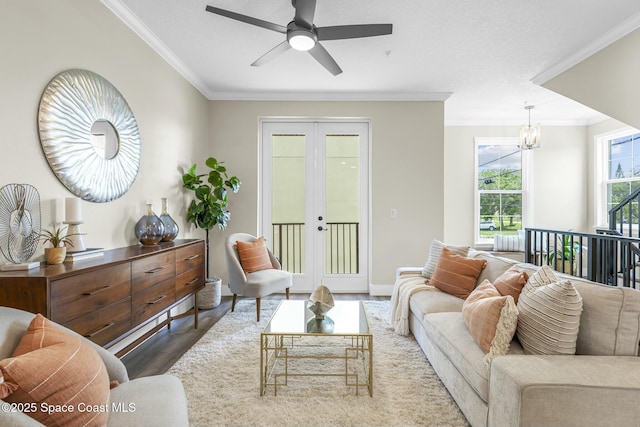 living room with ornamental molding, ceiling fan with notable chandelier, hardwood / wood-style floors, and french doors