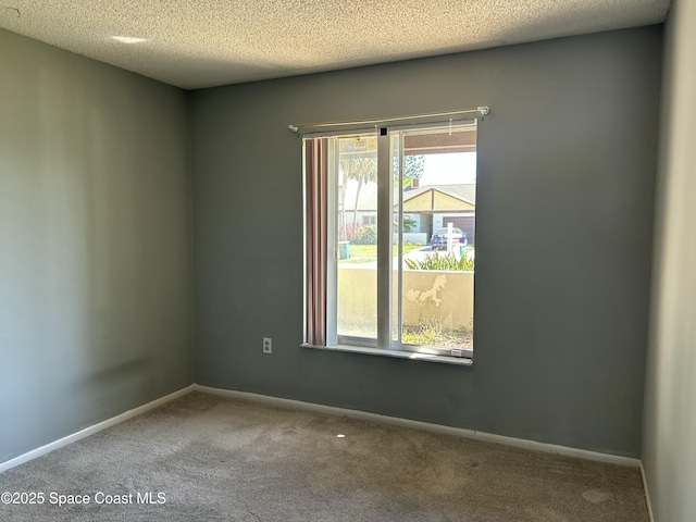 carpeted empty room featuring a textured ceiling and baseboards