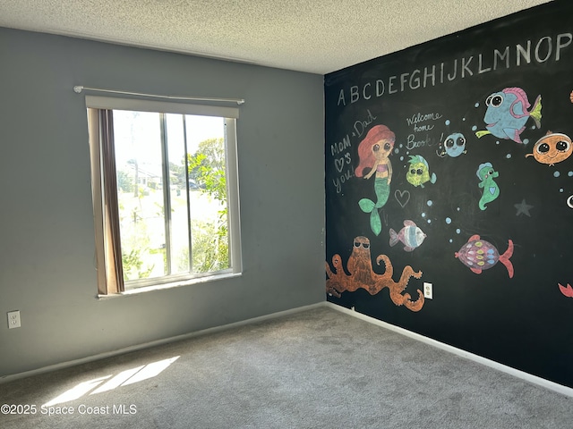 carpeted spare room with a wealth of natural light, a textured ceiling, and baseboards