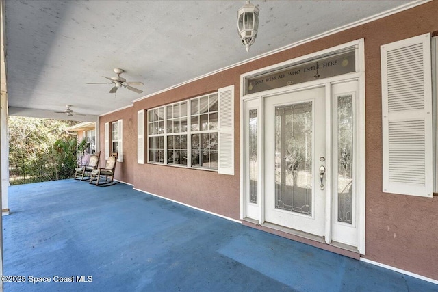 view of exterior entry featuring ceiling fan and a patio area