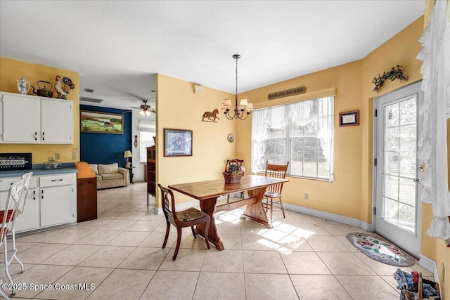 tiled dining space with ceiling fan with notable chandelier, a textured ceiling, and a healthy amount of sunlight