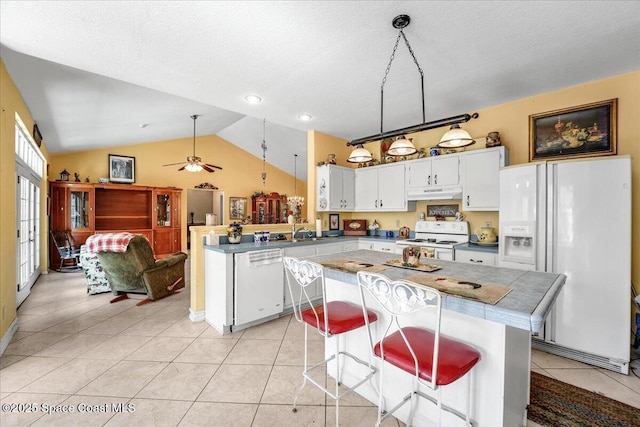 kitchen featuring white cabinetry, a kitchen breakfast bar, light tile patterned floors, kitchen peninsula, and white appliances