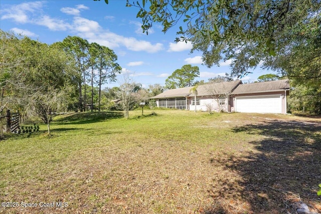 view of yard featuring a garage and a sunroom