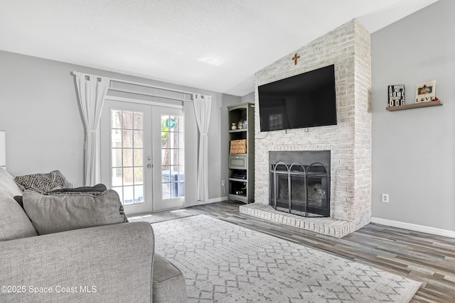 living room with a fireplace, lofted ceiling, hardwood / wood-style flooring, a textured ceiling, and french doors