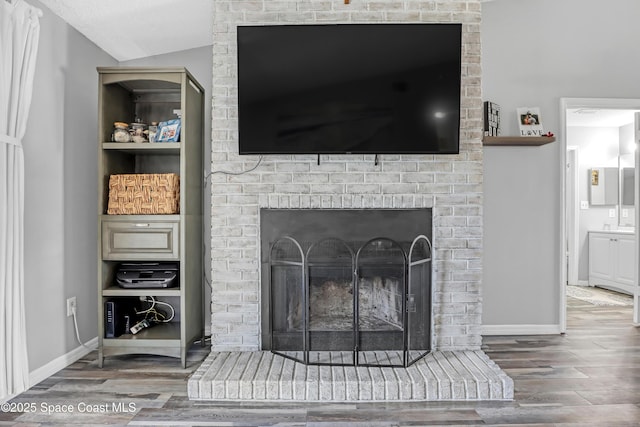 interior details with wood-type flooring and a brick fireplace