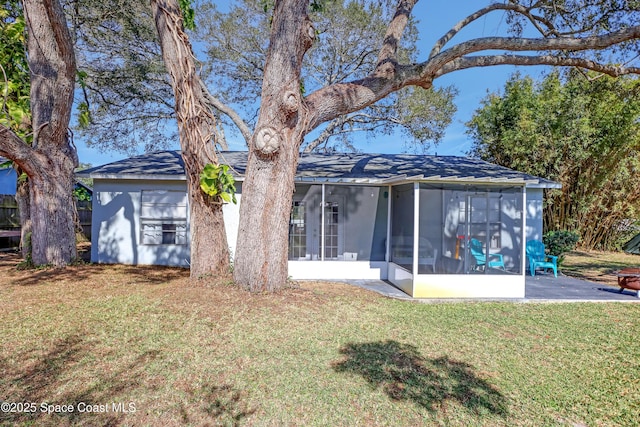 back of house with a sunroom, a patio area, and a lawn