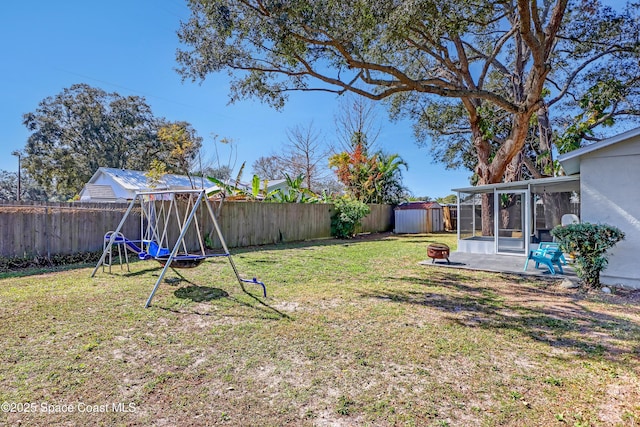 view of yard with a playground, a sunroom, a storage unit, and a patio area