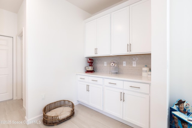 bar with tasteful backsplash and white cabinets