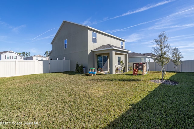 back of property featuring a playground and a lawn