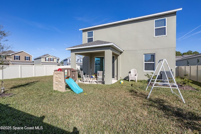 rear view of house with a yard and a playground