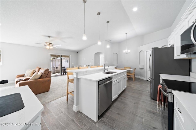 kitchen featuring pendant lighting, sink, appliances with stainless steel finishes, white cabinets, and a center island with sink