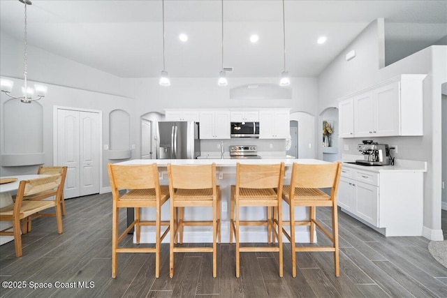 kitchen featuring stainless steel appliances, hanging light fixtures, and a center island with sink