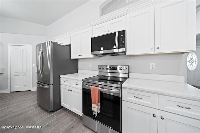 kitchen with white cabinetry, stainless steel appliances, and light stone countertops