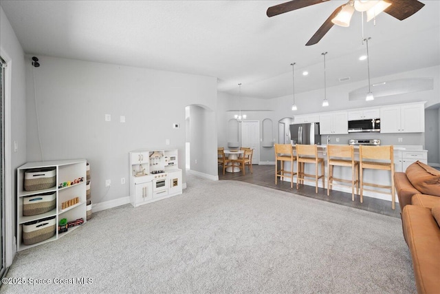 living room featuring ceiling fan with notable chandelier and carpet