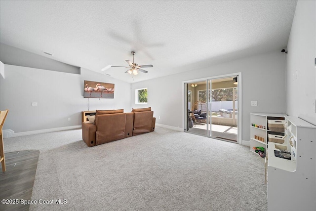 carpeted living room with ceiling fan, vaulted ceiling, and a textured ceiling