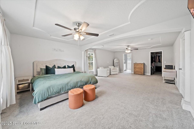 bedroom featuring ceiling fan, a spacious closet, a textured ceiling, and carpet