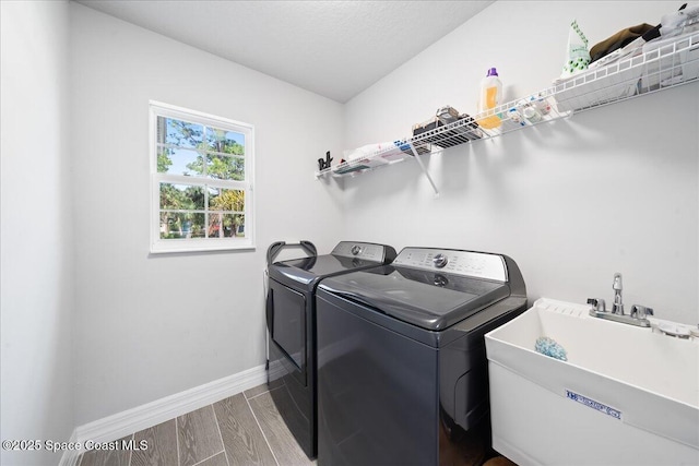 washroom with sink, washing machine and dryer, and light wood-type flooring