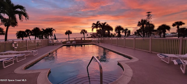 pool at dusk with a patio area