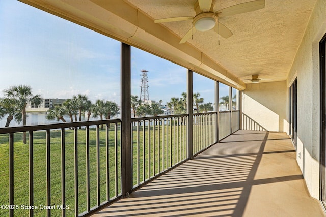 balcony with a water view and a ceiling fan