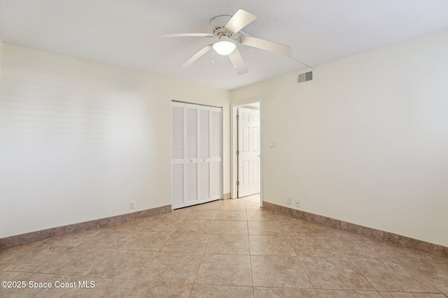 spare room with light tile patterned floors, visible vents, baseboards, and ceiling fan