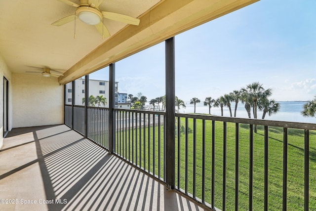 unfurnished sunroom with ceiling fan and a water view