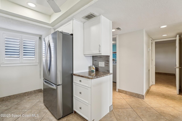 kitchen featuring visible vents, dark countertops, white cabinetry, freestanding refrigerator, and light tile patterned floors