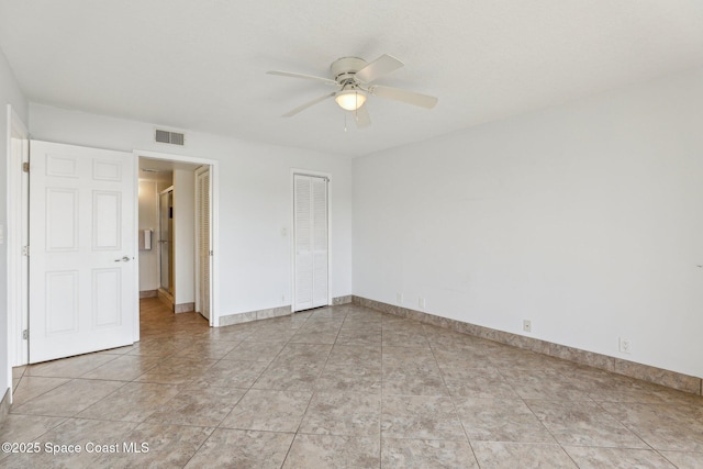 unfurnished room featuring light tile patterned floors, visible vents, baseboards, and a ceiling fan