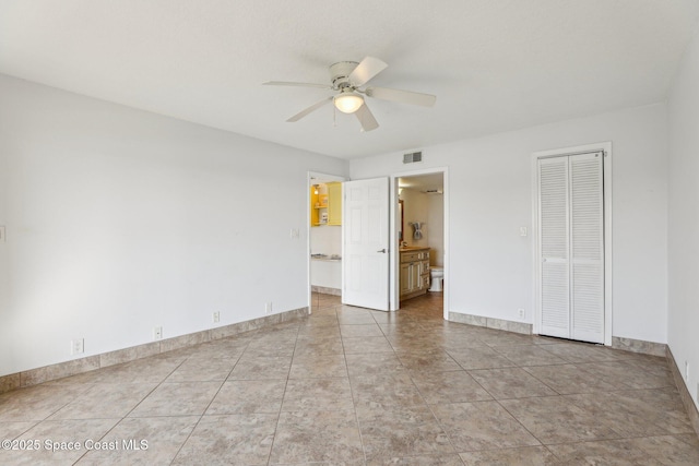 unfurnished bedroom with light tile patterned floors, a closet, ceiling fan, and ensuite bathroom