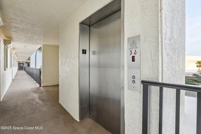 hallway with elevator and concrete floors