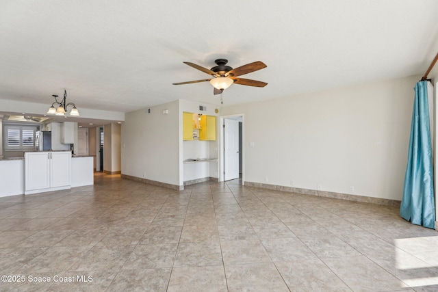 unfurnished living room with light tile patterned floors, ceiling fan with notable chandelier, and baseboards