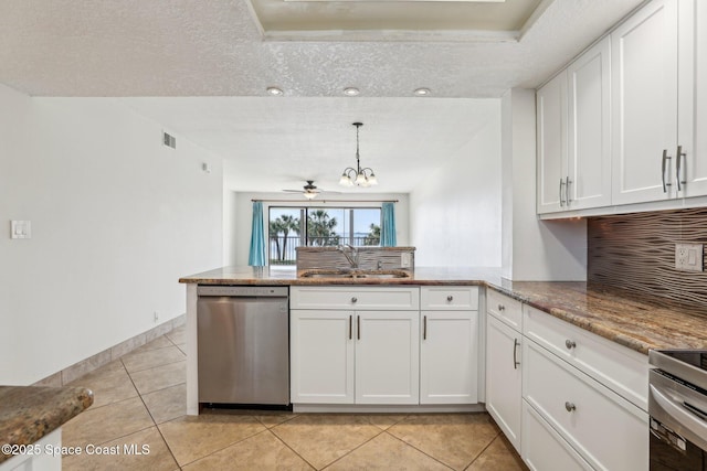 kitchen with a peninsula, an inviting chandelier, white cabinets, stainless steel appliances, and a sink