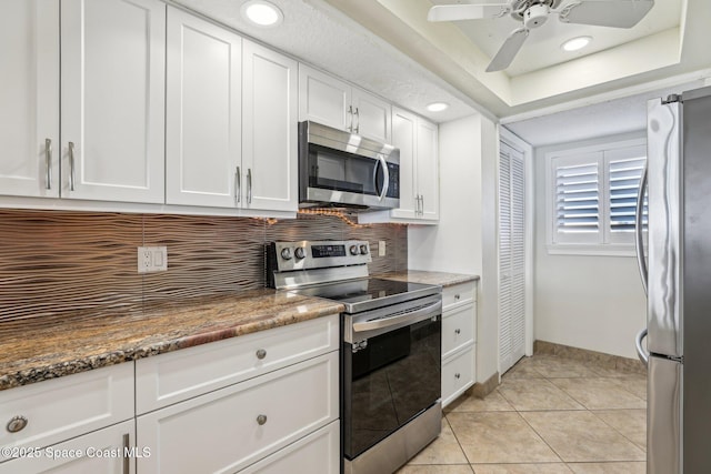 kitchen featuring light tile patterned floors, dark stone counters, white cabinets, and appliances with stainless steel finishes