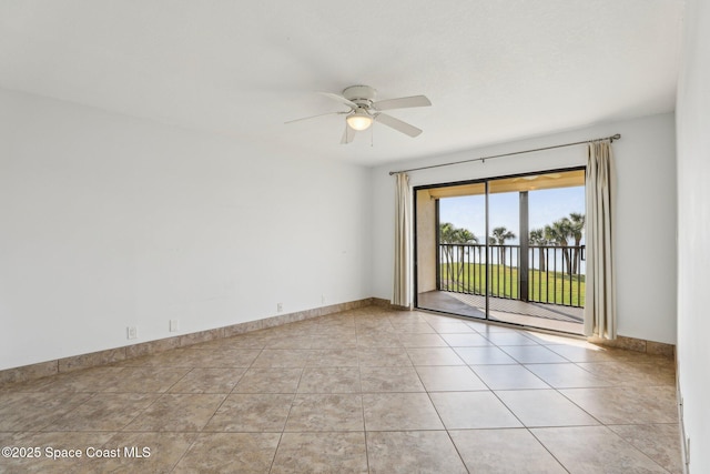 empty room featuring light tile patterned floors, a ceiling fan, and baseboards