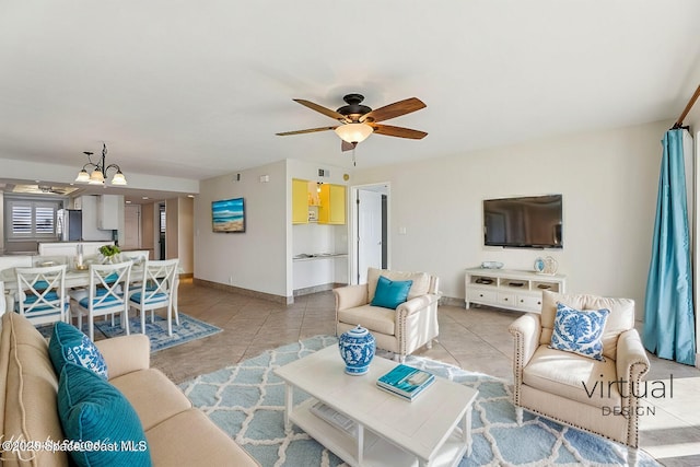 living room with light tile patterned floors, ceiling fan with notable chandelier, and baseboards